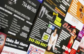 Board hanging on the wall with many post cards advertising business services